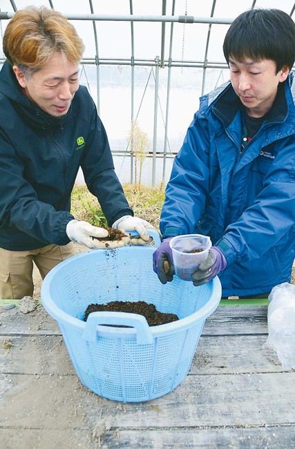 発酵鶏ふんの状態を確認する大島社長(左)と養鶏業者(新潟県関川村で)