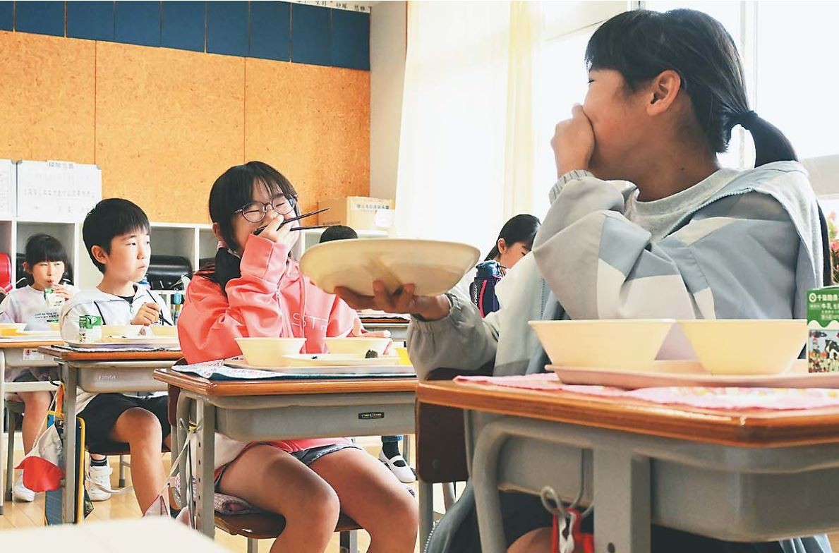 おしゃべりしながら給食を食べる子どもたち。机はまだ前を向いたままだ（千葉県いすみ市で）