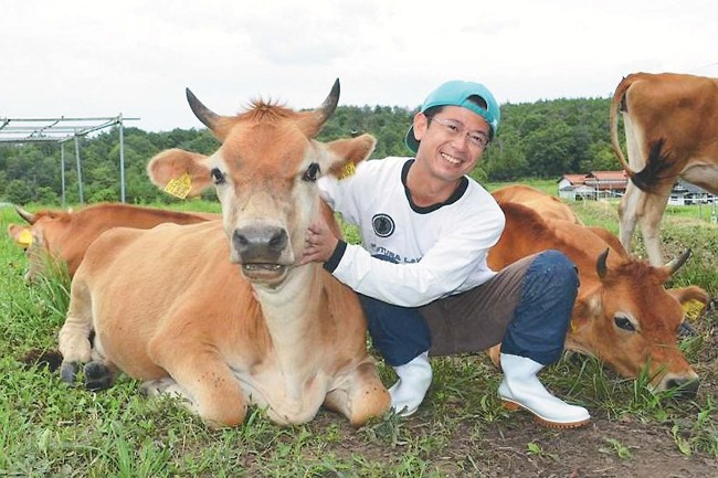 ジャージー牛とたわむれる織田さん（広島県三次市で＝織田さん提供）