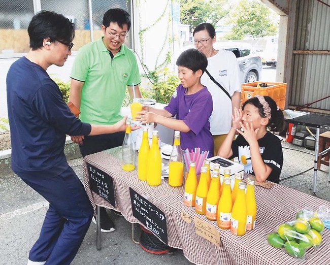 イベントで規格外かんきつを使ったジュースを販売する鈴木さん（左から２人目）（松山市で）