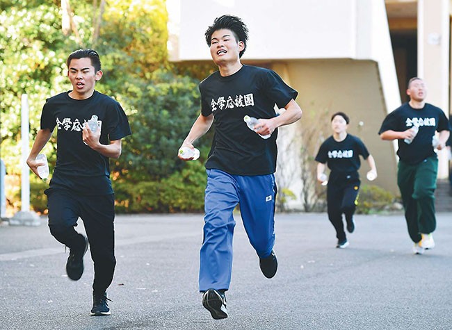 ダイコンに見立てたペットボトルを持って走る団員(東京都世田谷区で=鴻田寛之写す)