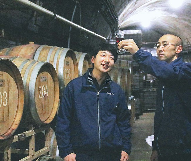 ワイン貯蔵庫でテイスティングする山口さん（右）と板垣さん（山形県鶴岡市で）