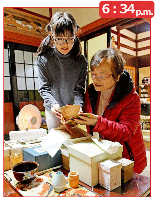 帰宅し夕食までの間、孫の佳音さん（左）と茶器を眺める谷井さん。茶道は表千家教授の資格を持つ腕前だ