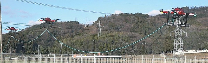先頭のドローンにつなげた送電ケーブルとホースを持ち上げる後続のドローン（福井県工業技術センター提供）