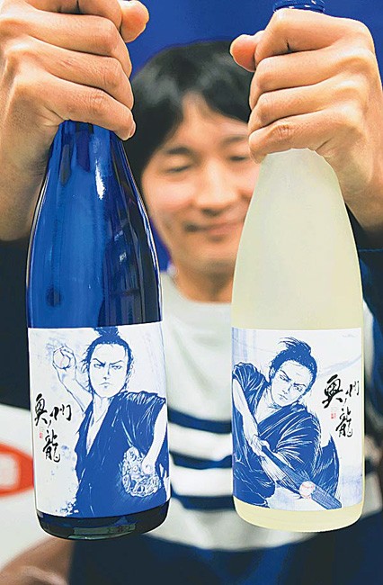 ドジャースカラーの日本酒「奥州ノ龍」を持つ及川専務（岩手県奥州市で）